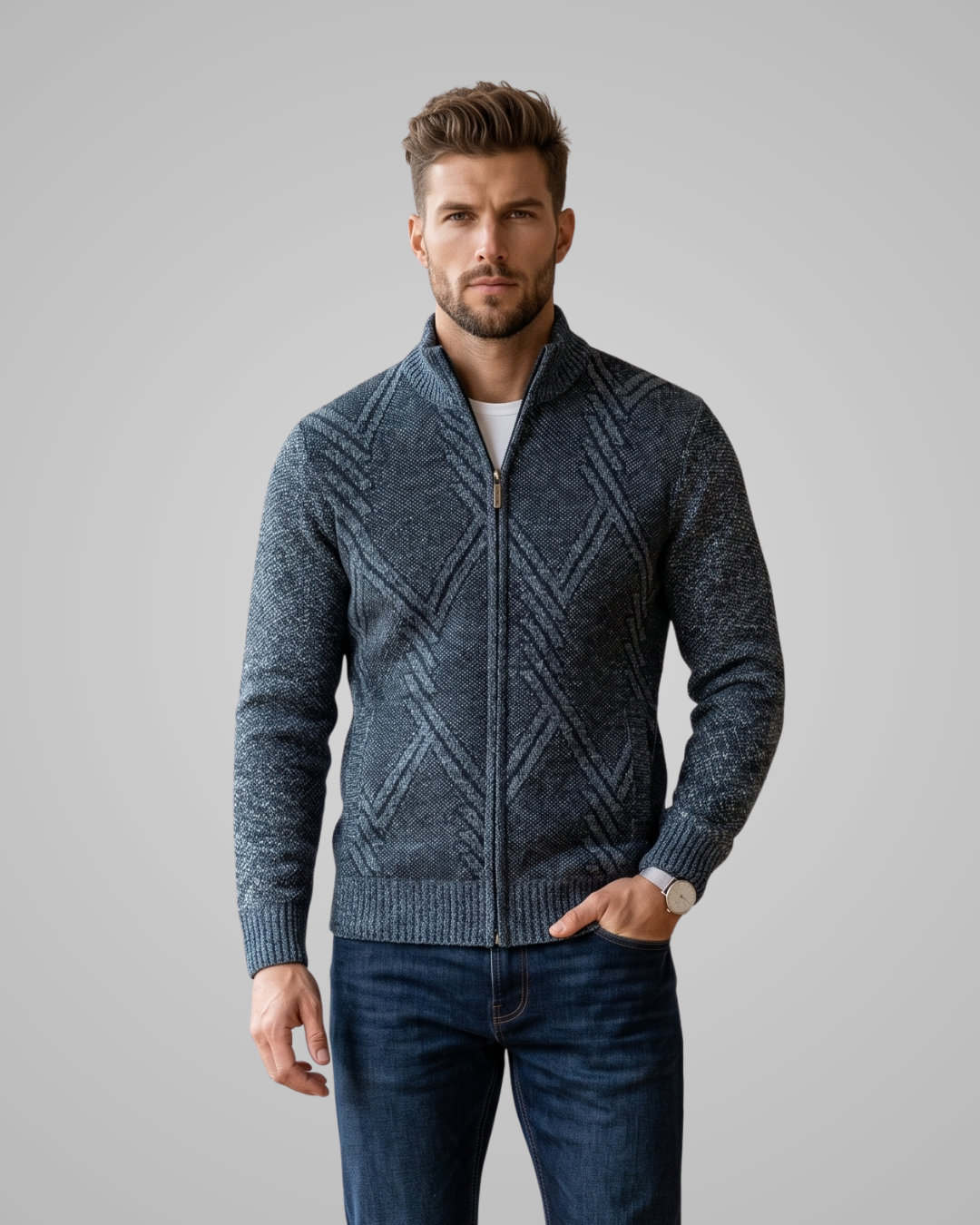 Man wearing a blue patterned sweater and jeans on a gray background