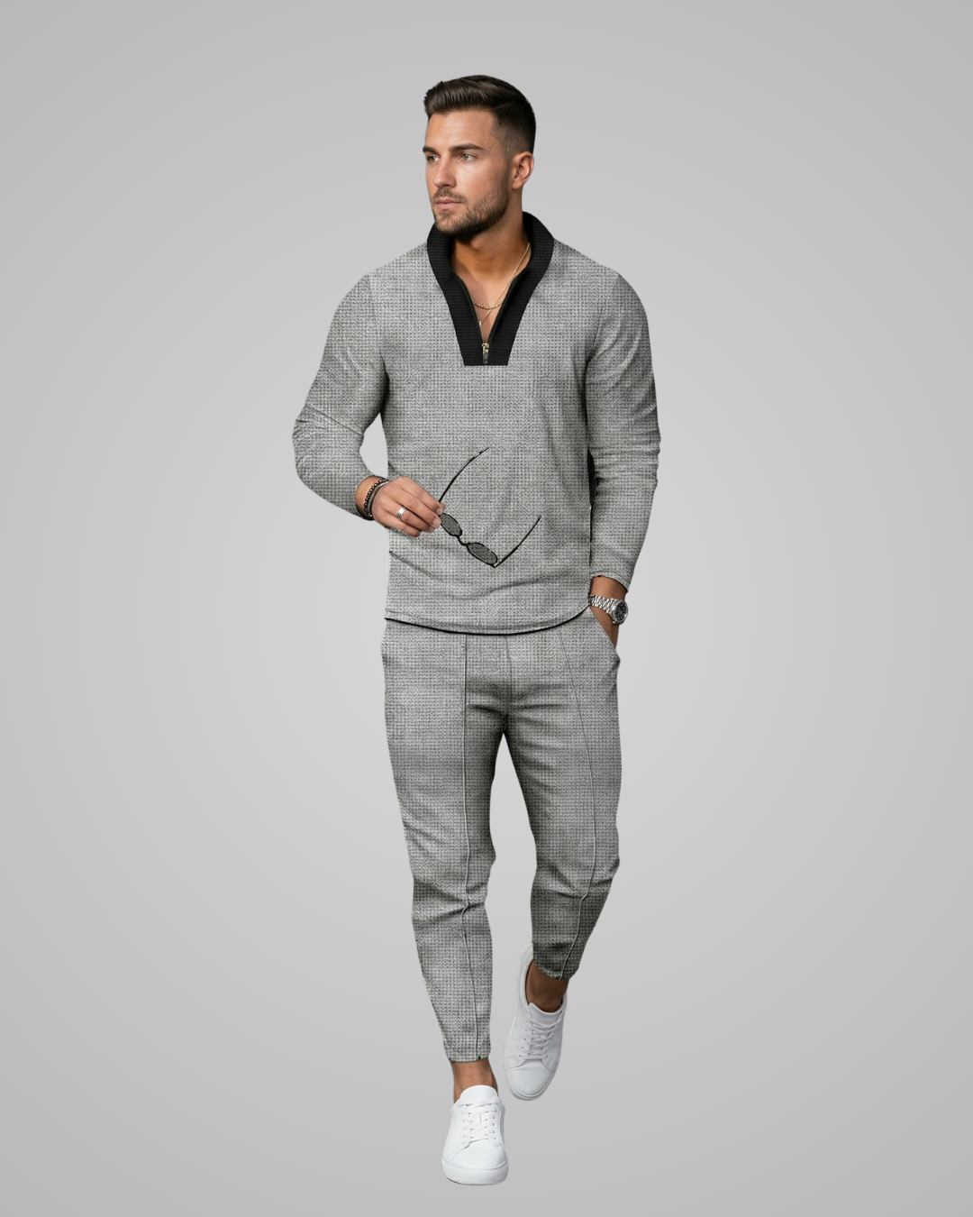 Man wearing a gray sweater and pants with white sneakers on a gray background