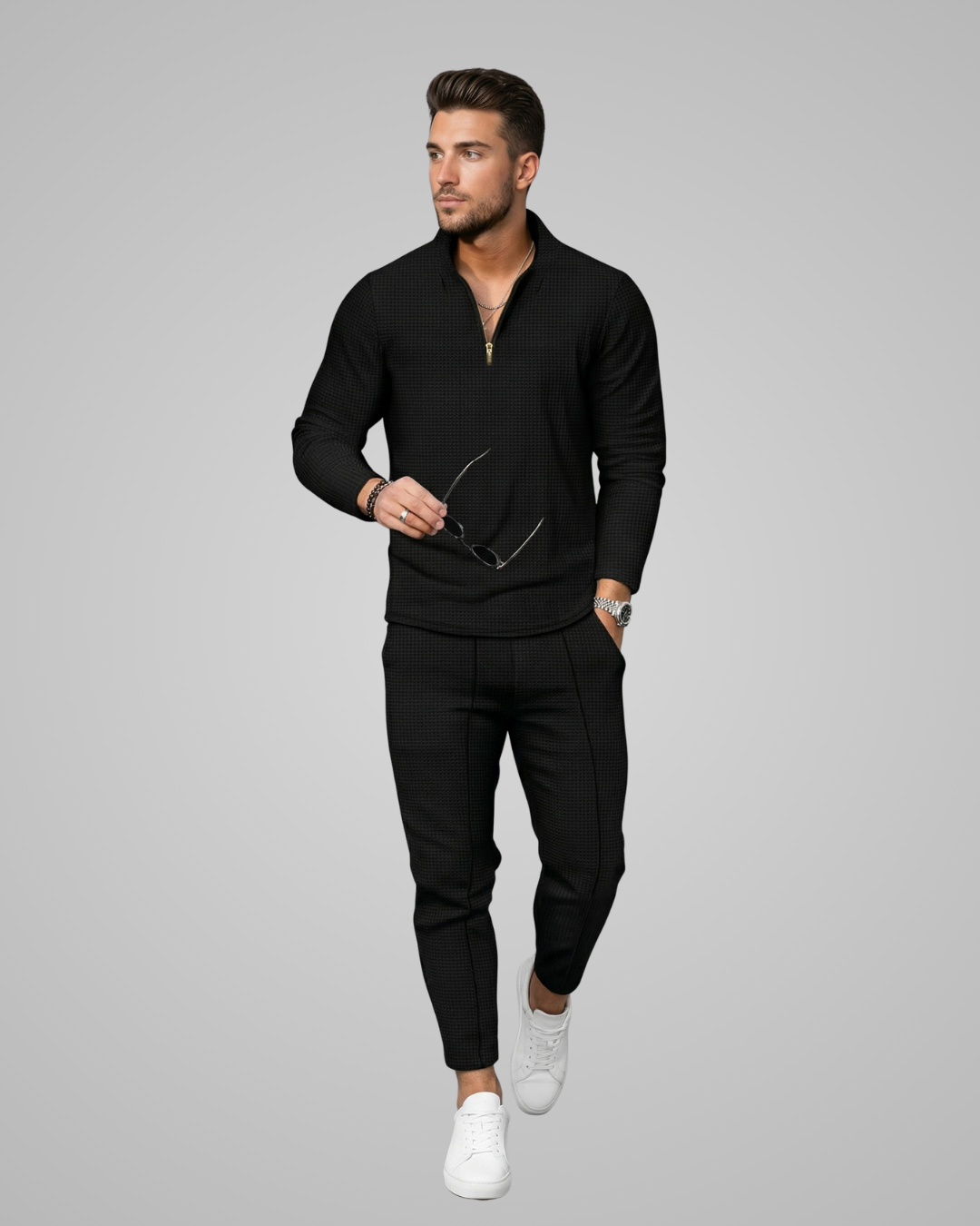 Man wearing a black outfit with white shoes on a gray background