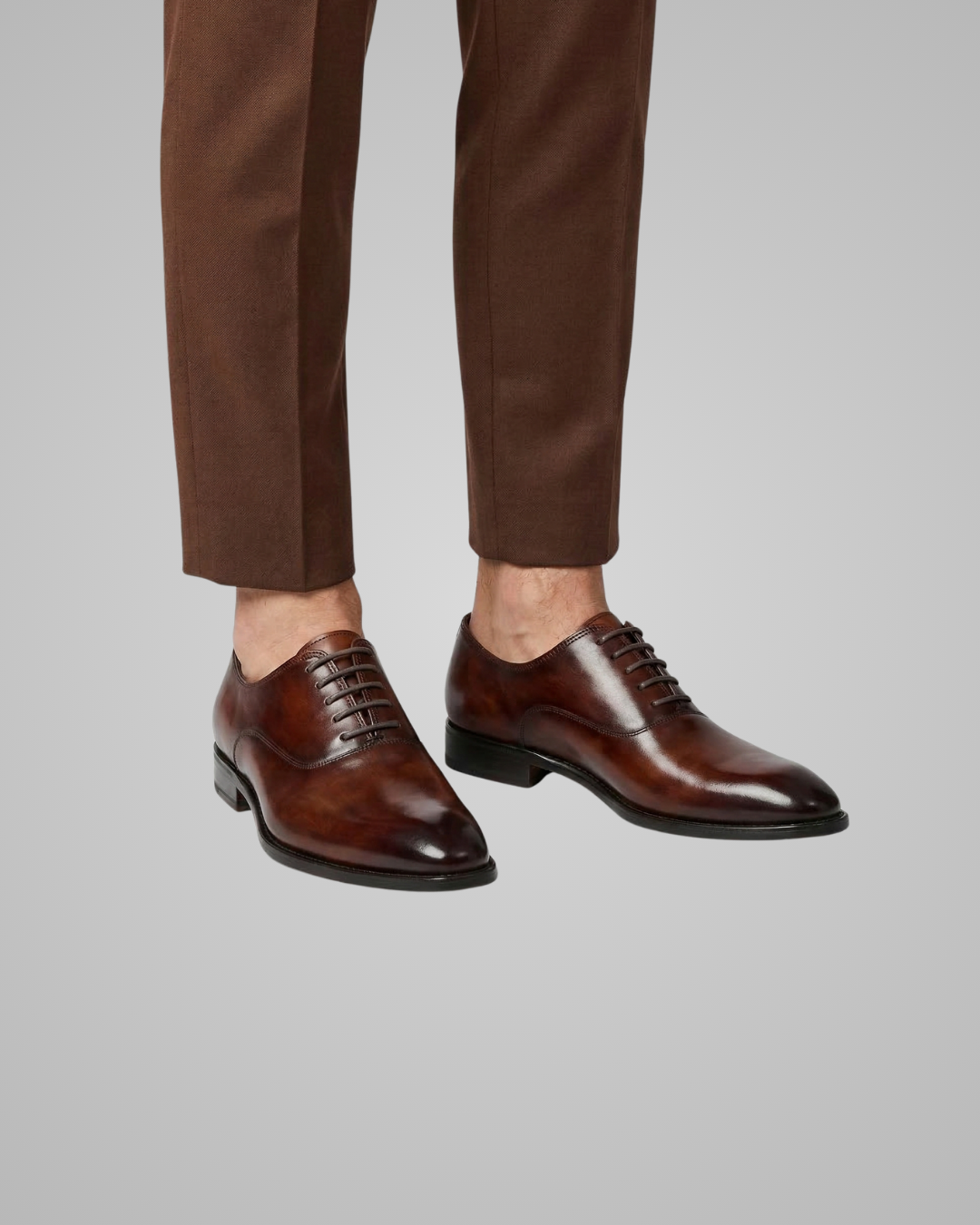 Brown dress shoes and pants on a gray background