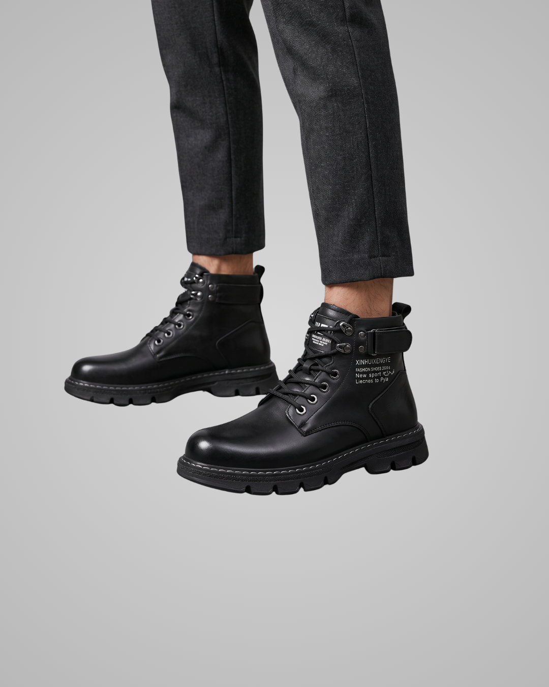 Black boots worn with black pants on a gray background