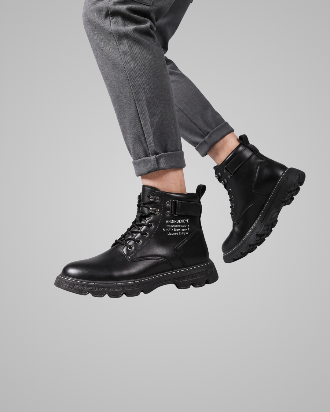 Black boots worn with gray pants on a gray background