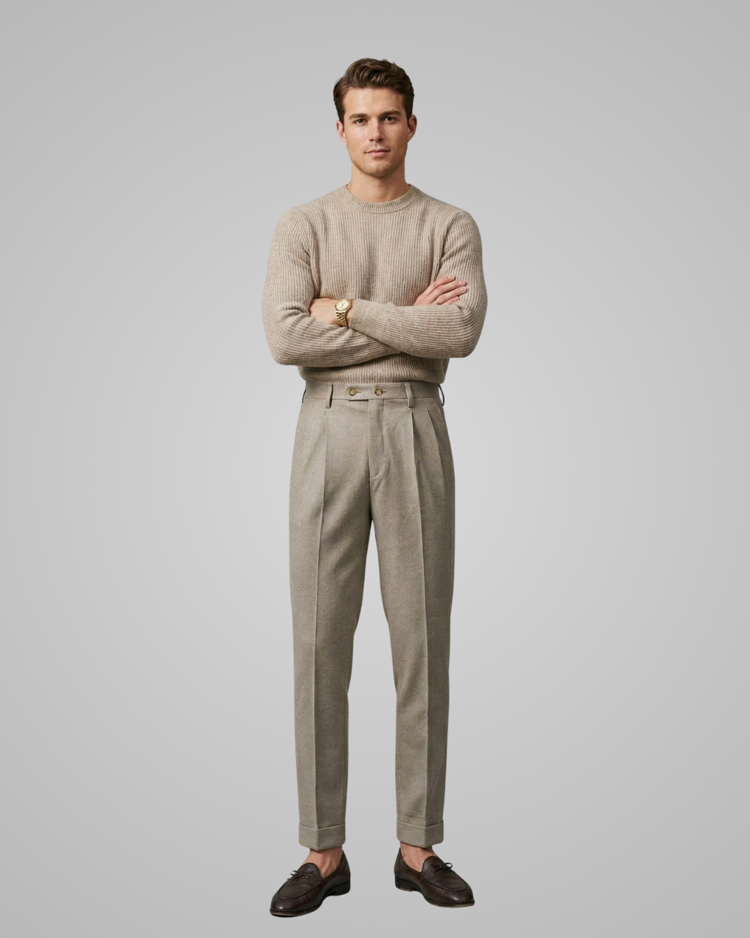 Man wearing a beige sweater and pants standing against a plain background