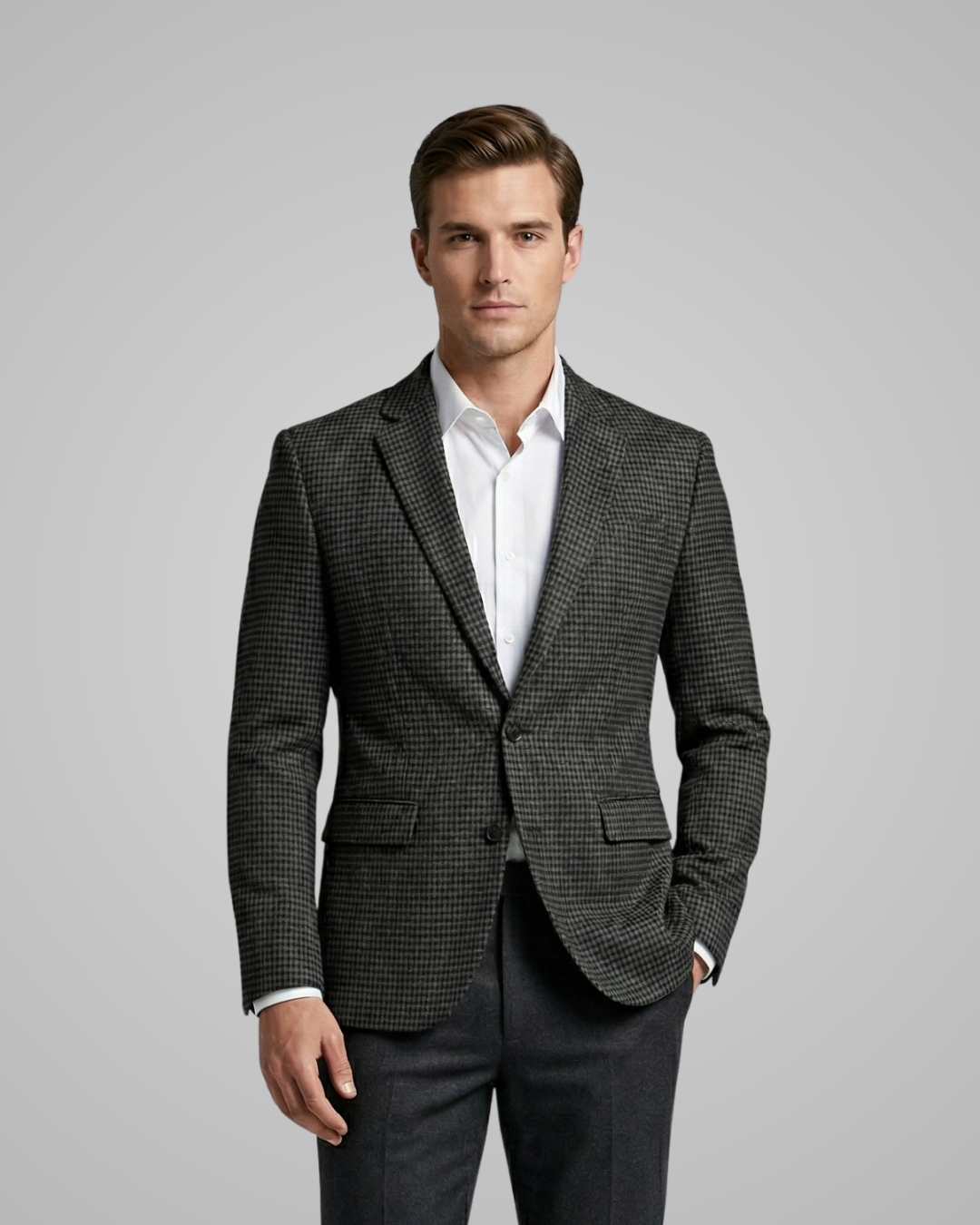 Man wearing a gray checkered blazer over a white shirt on a gray background