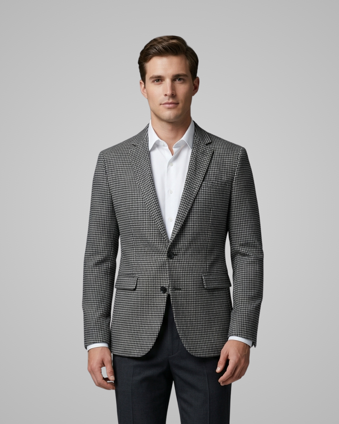 Man wearing a gray checkered blazer over a white shirt on a gray background