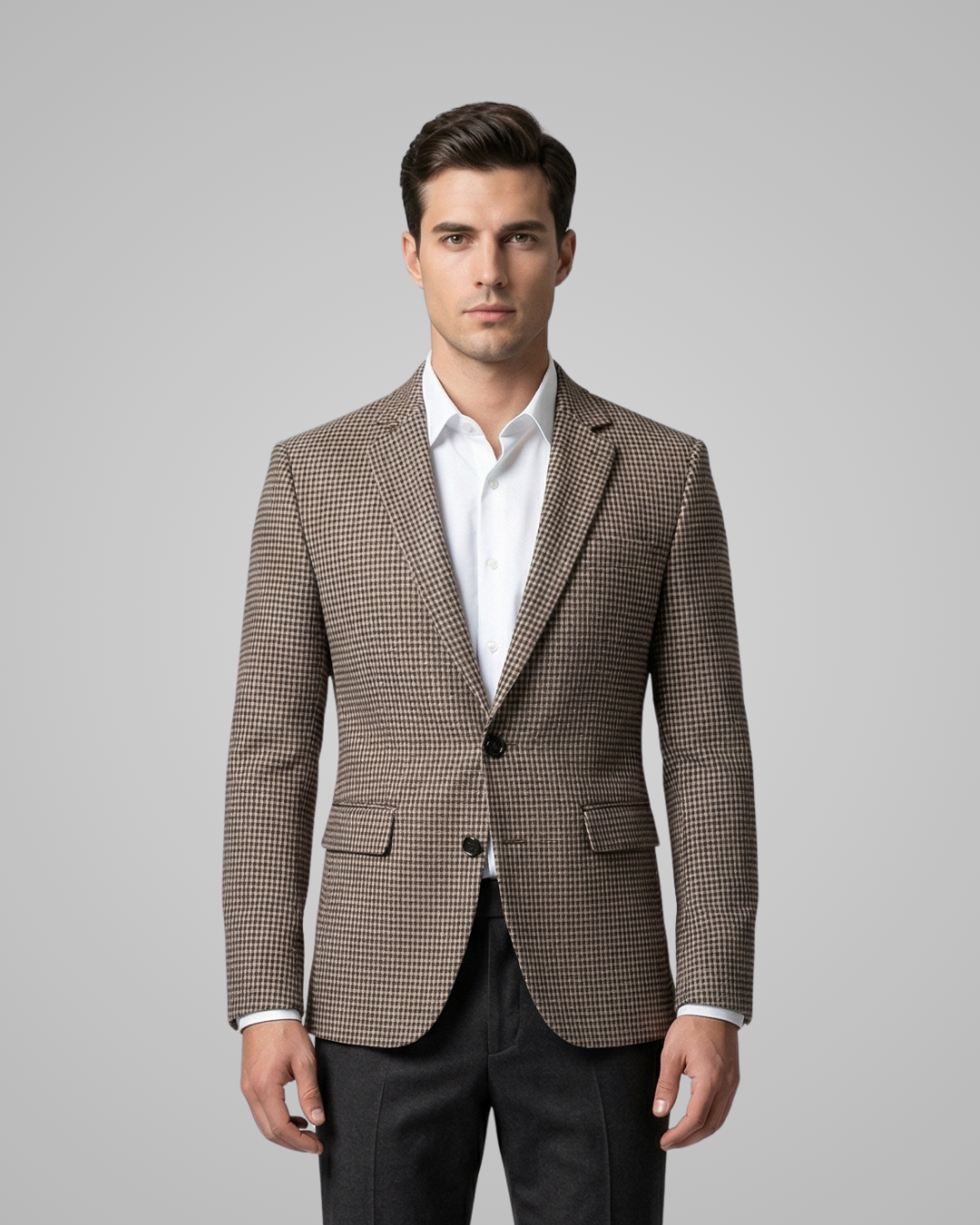 Man wearing a brown checkered blazer over a white shirt on a gray background