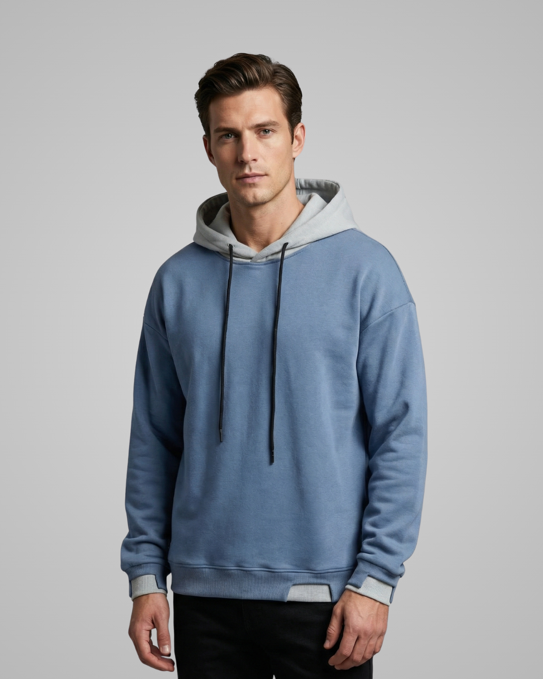 Man wearing a blue hoodie with a gray hood against a gray background