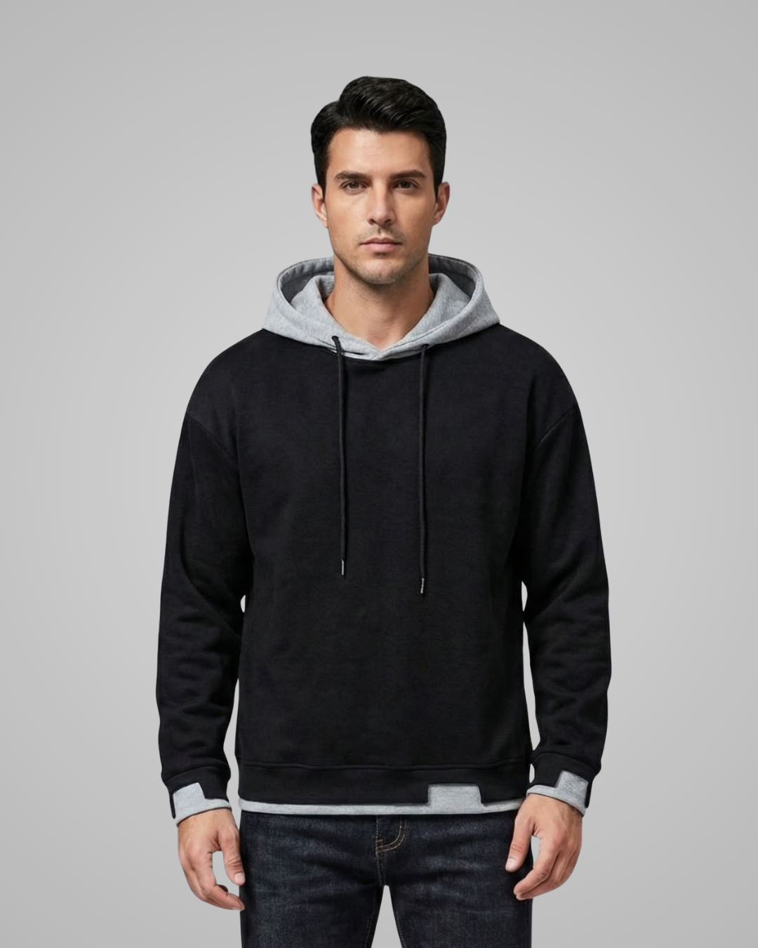 Man wearing a black hoodie with a gray hood against a gray background