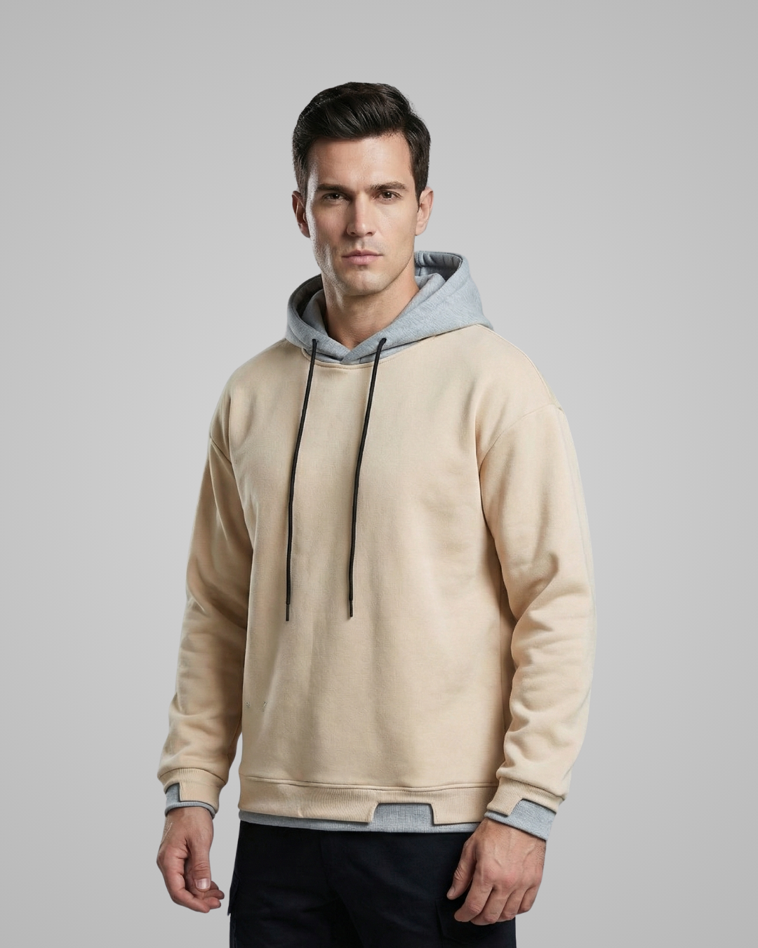 Man wearing a beige and gray hoodie on a gray background