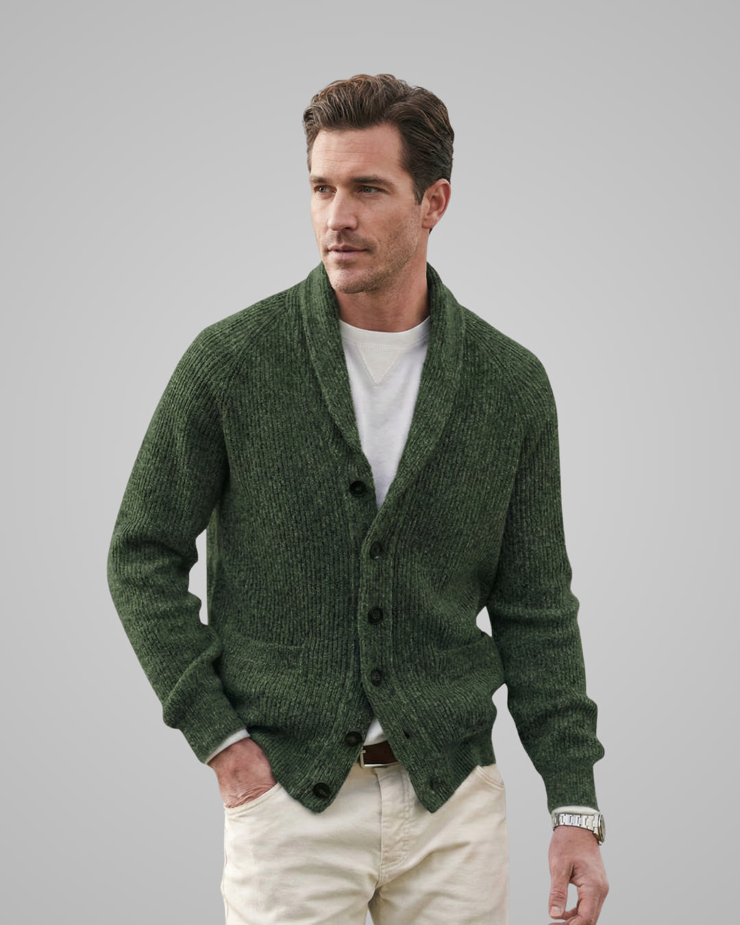 Man wearing a green cardigan over a white shirt on a gray background