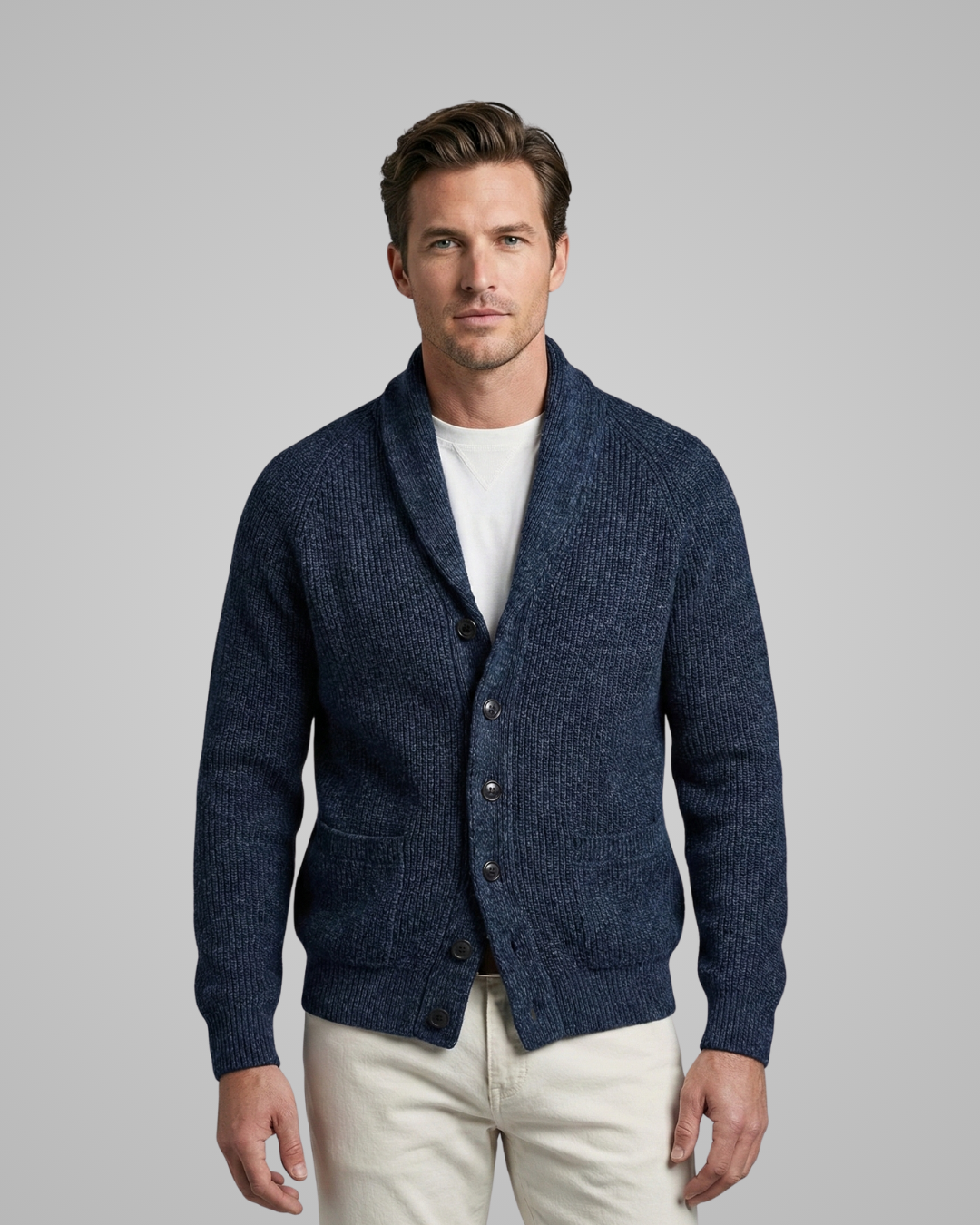 Man wearing a blue cardigan over a white shirt on a gray background