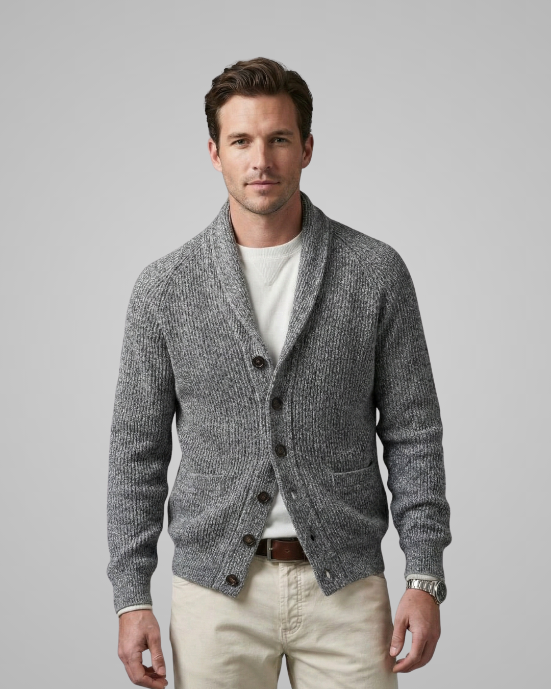 Man wearing a gray cardigan over a white shirt with beige pants on a light gray background
