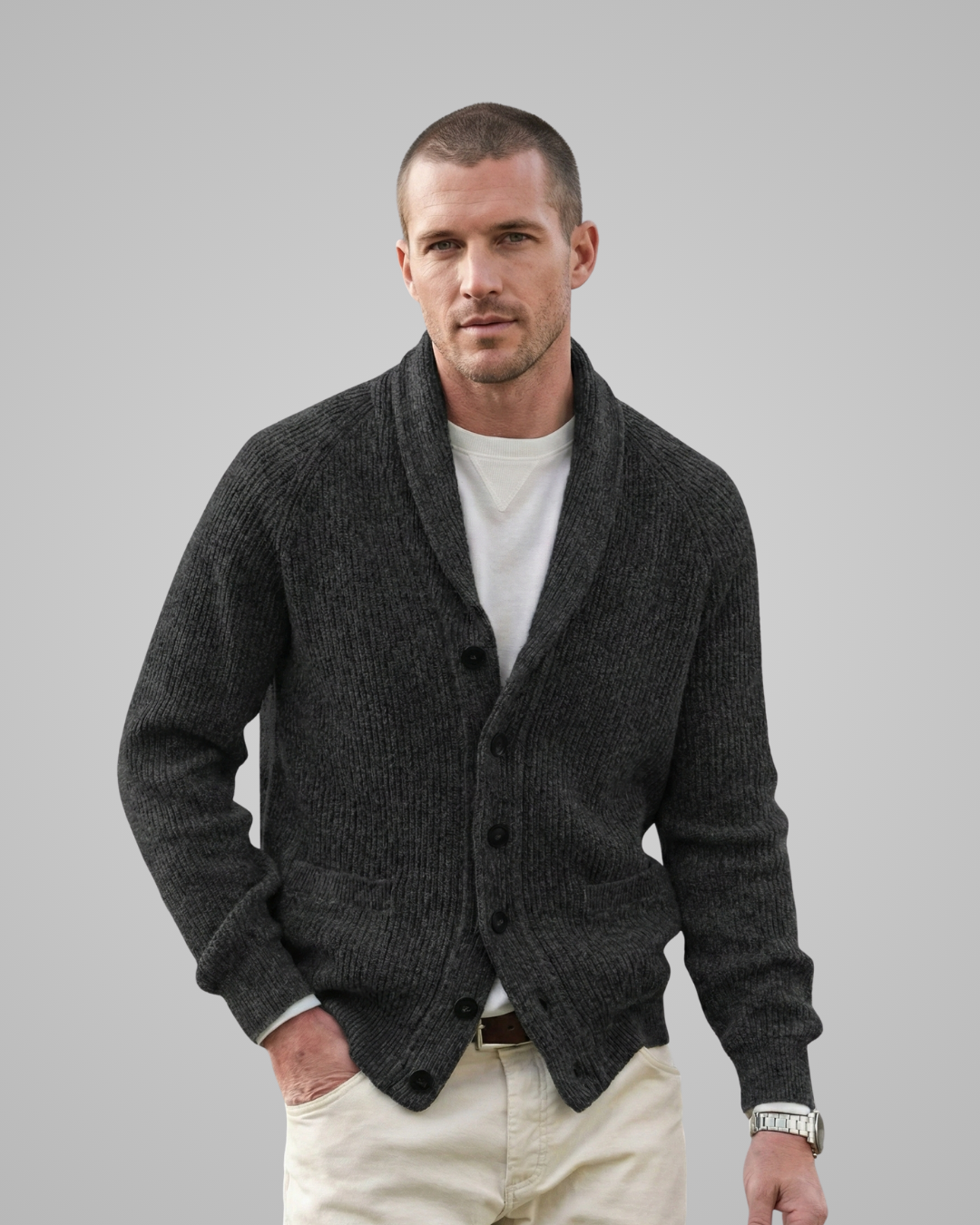 Man wearing a dark gray cardigan over a white shirt with beige pants on a light gray background
