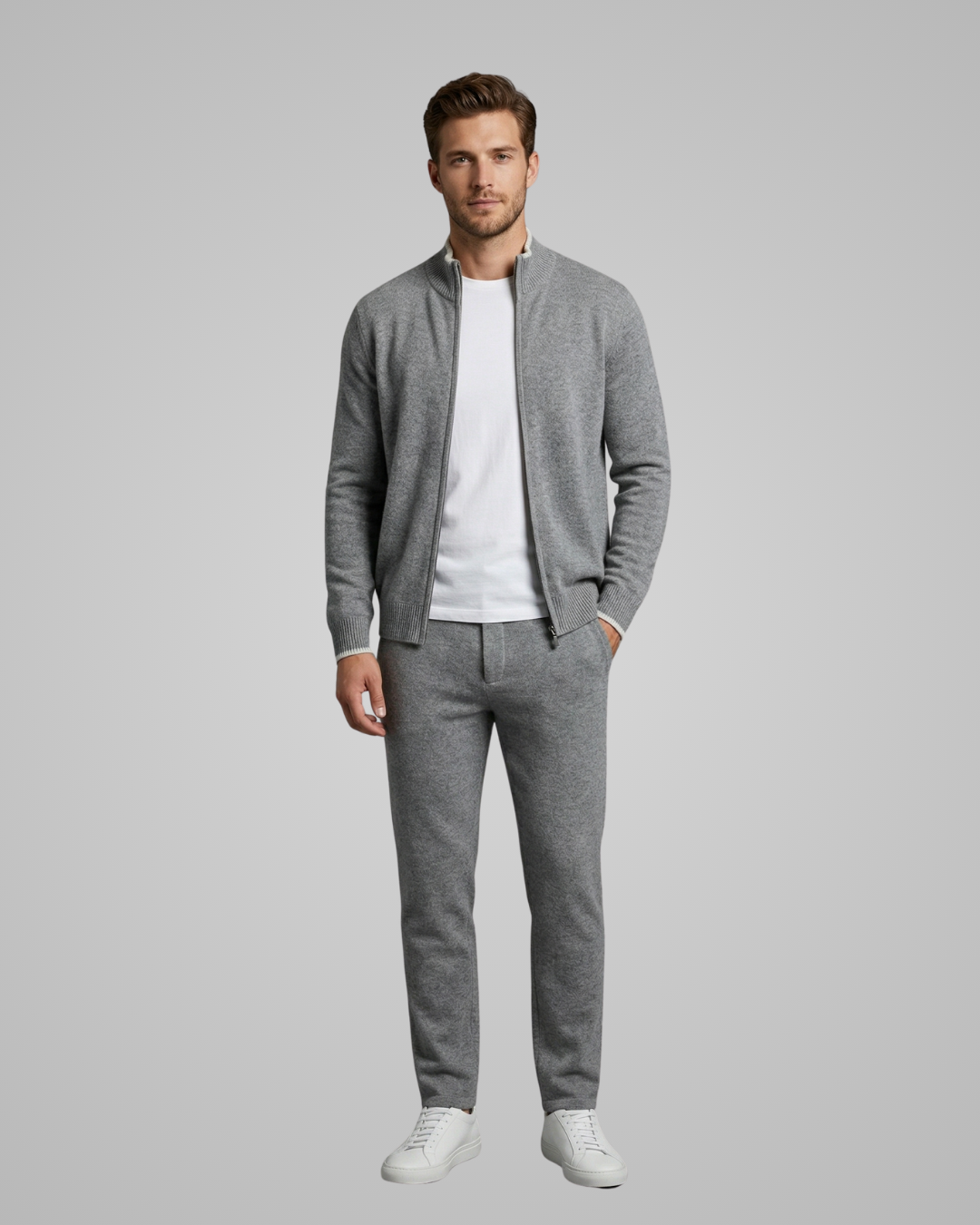 Man wearing a gray cardigan, white t-shirt, and gray pants on a gray background
