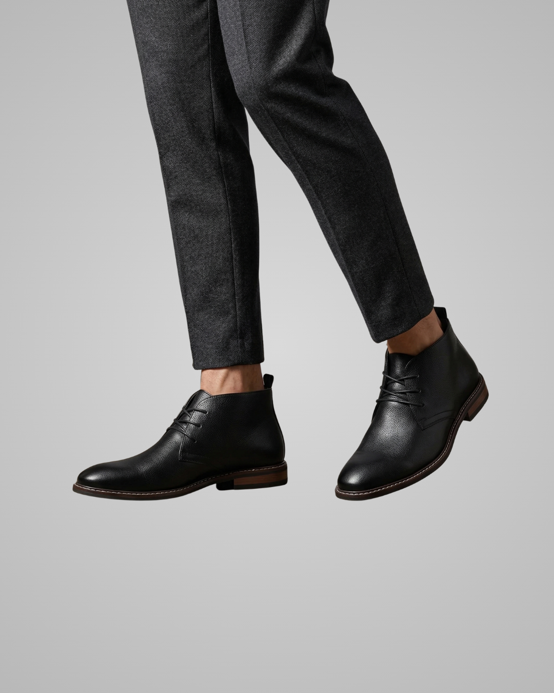 Black leather shoes worn with gray pants on a light gray background