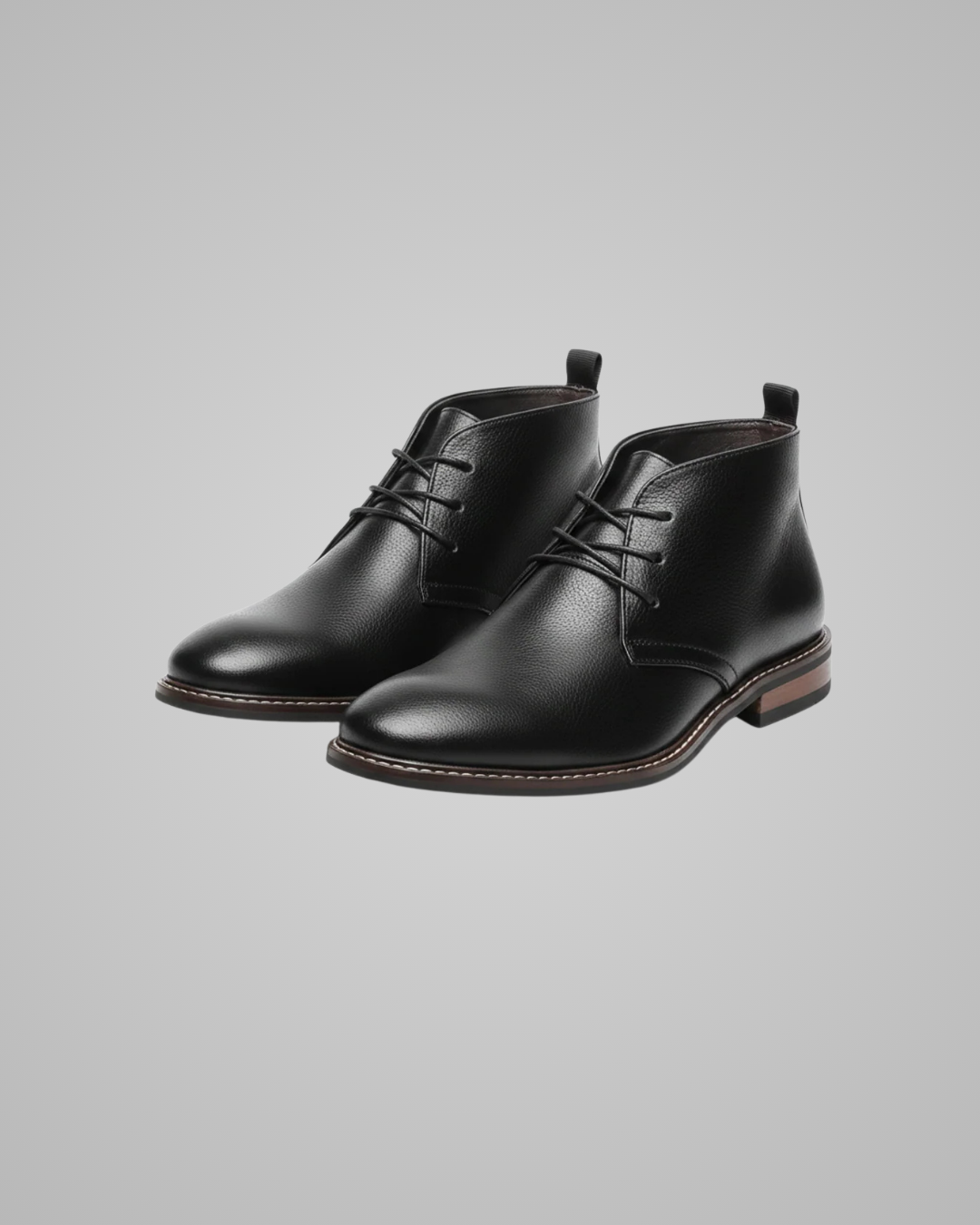 Pair of black leather boots on a gray background