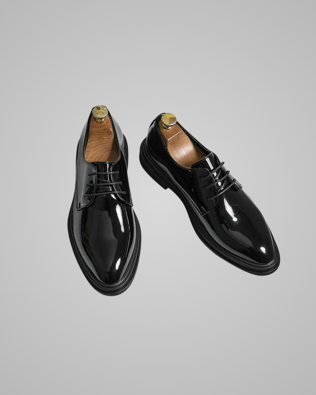 Pair of black patent leather shoes on a gray background