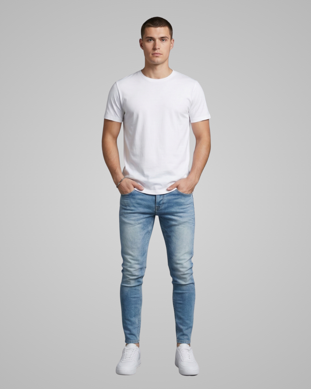 Man wearing a white t-shirt and light blue jeans on a gray background