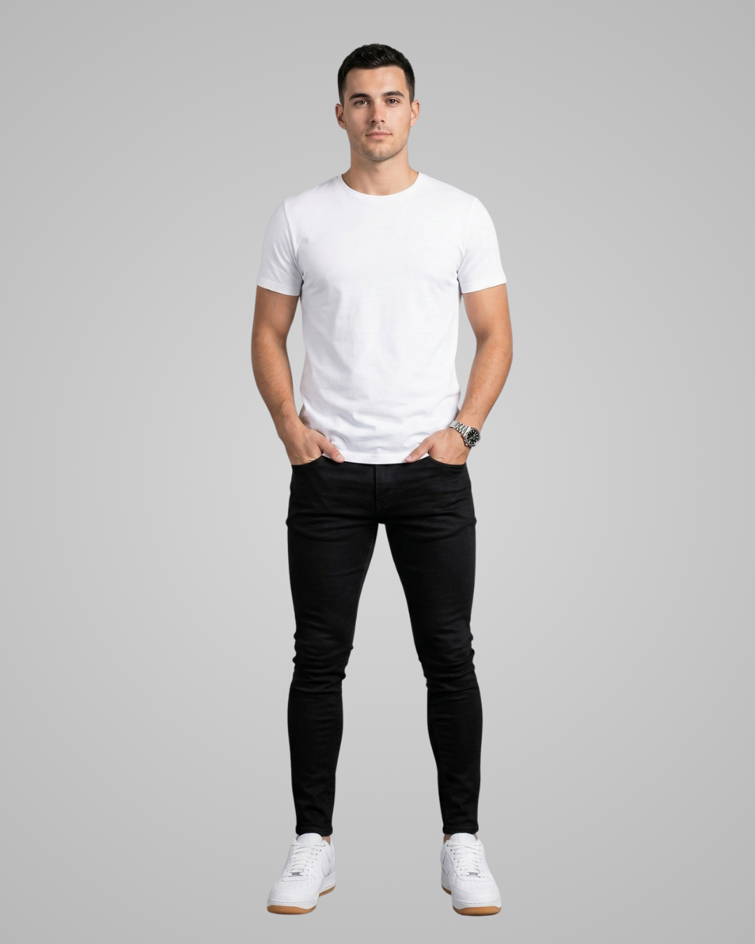 Man wearing a white t-shirt and black jeans on a gray background