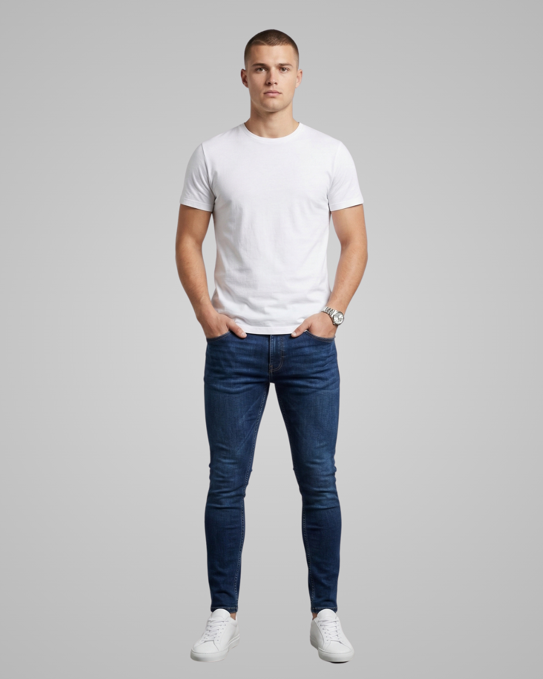 Man wearing a white t-shirt and blue jeans on a gray background