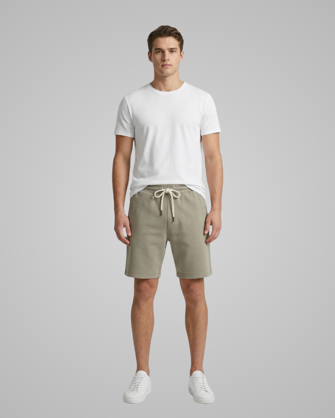 Man wearing a white t-shirt and beige shorts on a gray background