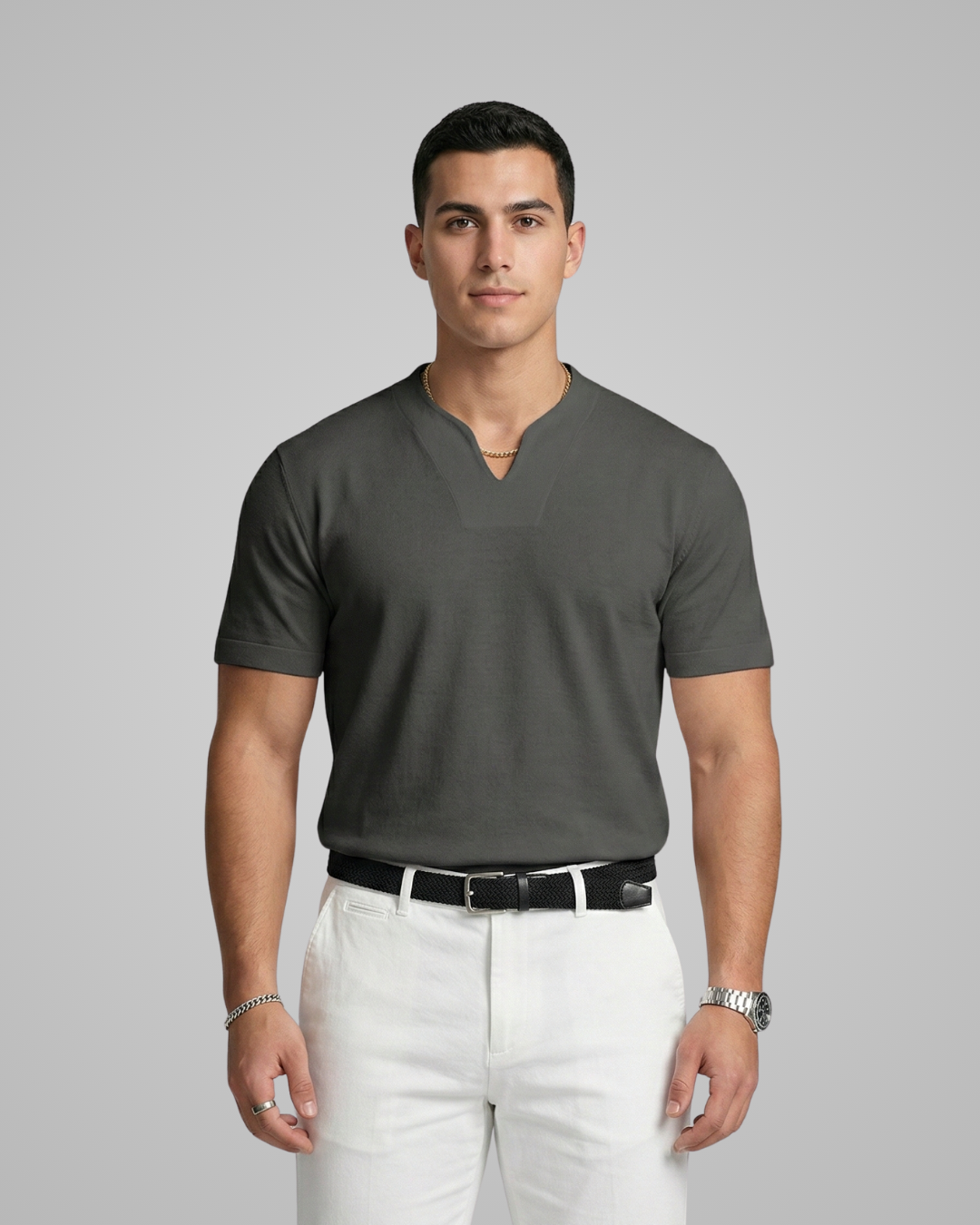 Man wearing a gray V-neck shirt and white pants on a gray background
