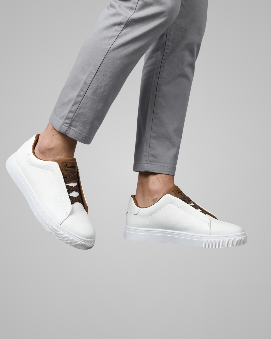 White sneakers with brown accents worn with gray pants on a light gray background