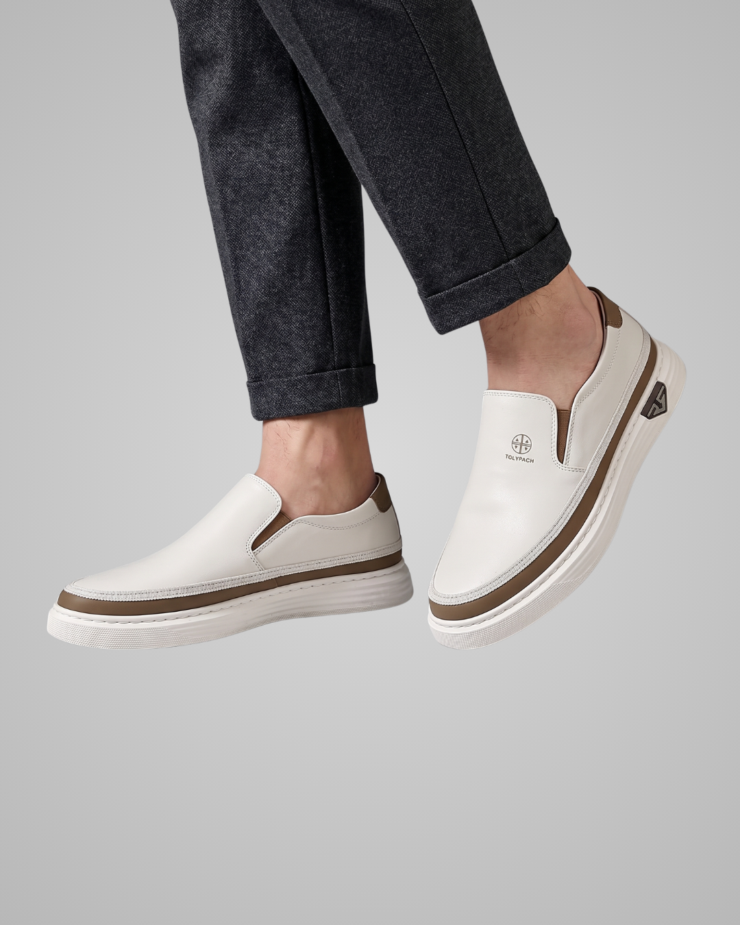 White slip-on shoes with white soles worn by a person on a gray background