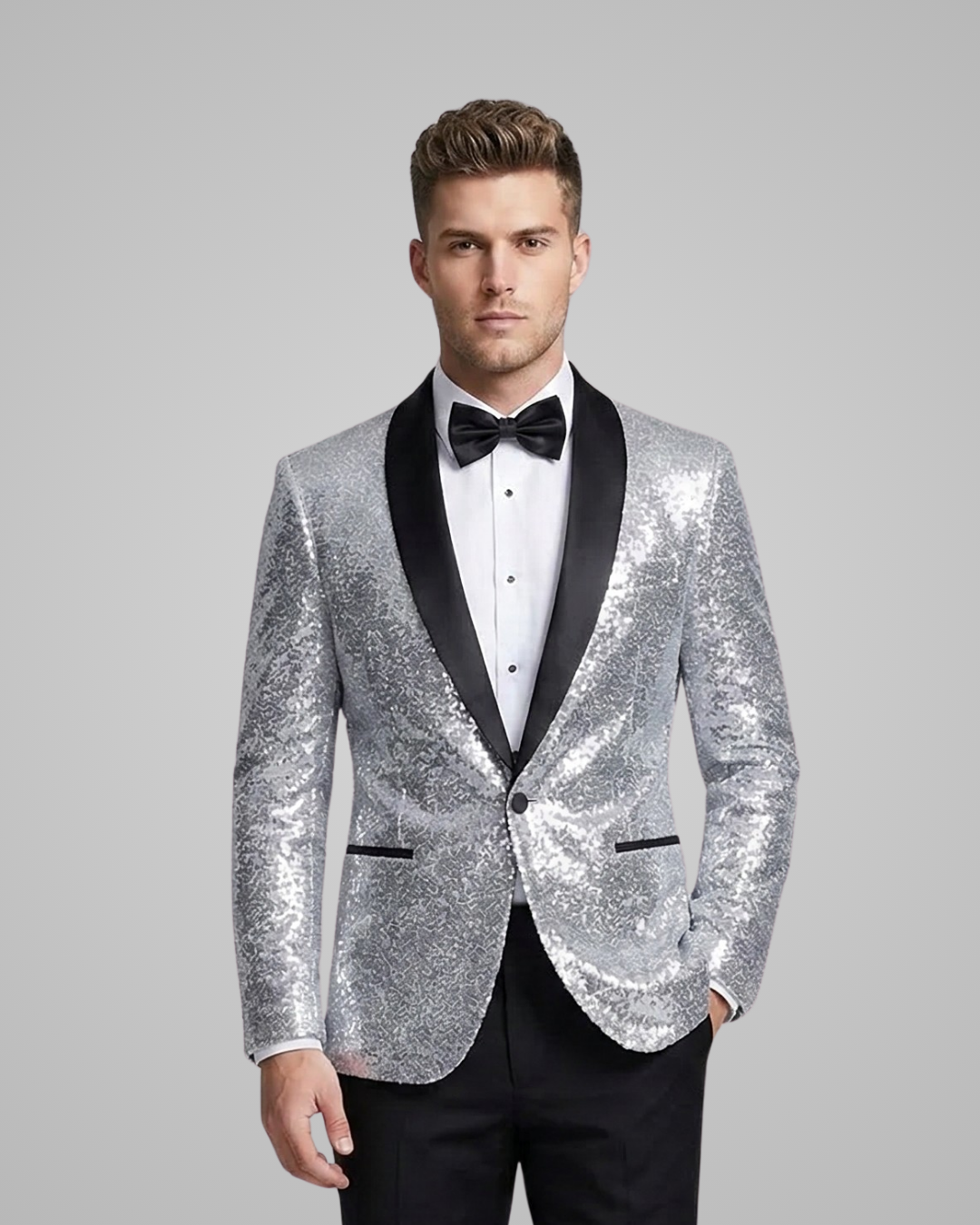Man wearing a silver sequin jacket with black lapels and bow tie on a gray background