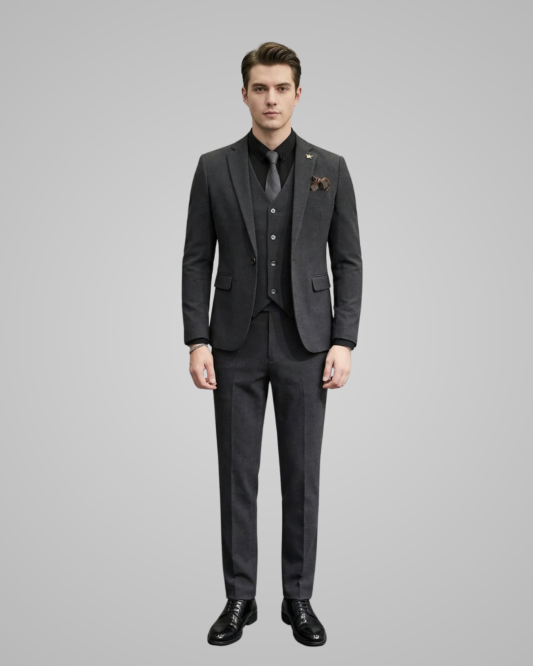 Man wearing a gray suit with a tie and pocket square on a gray background