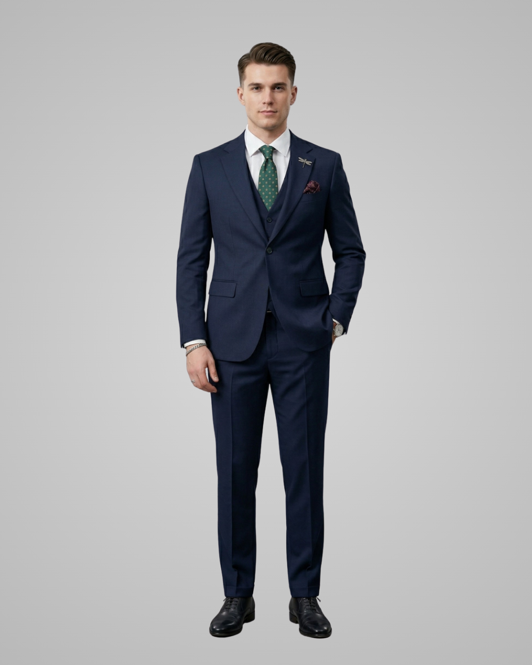 Man wearing a navy suit with a green tie on a gray background