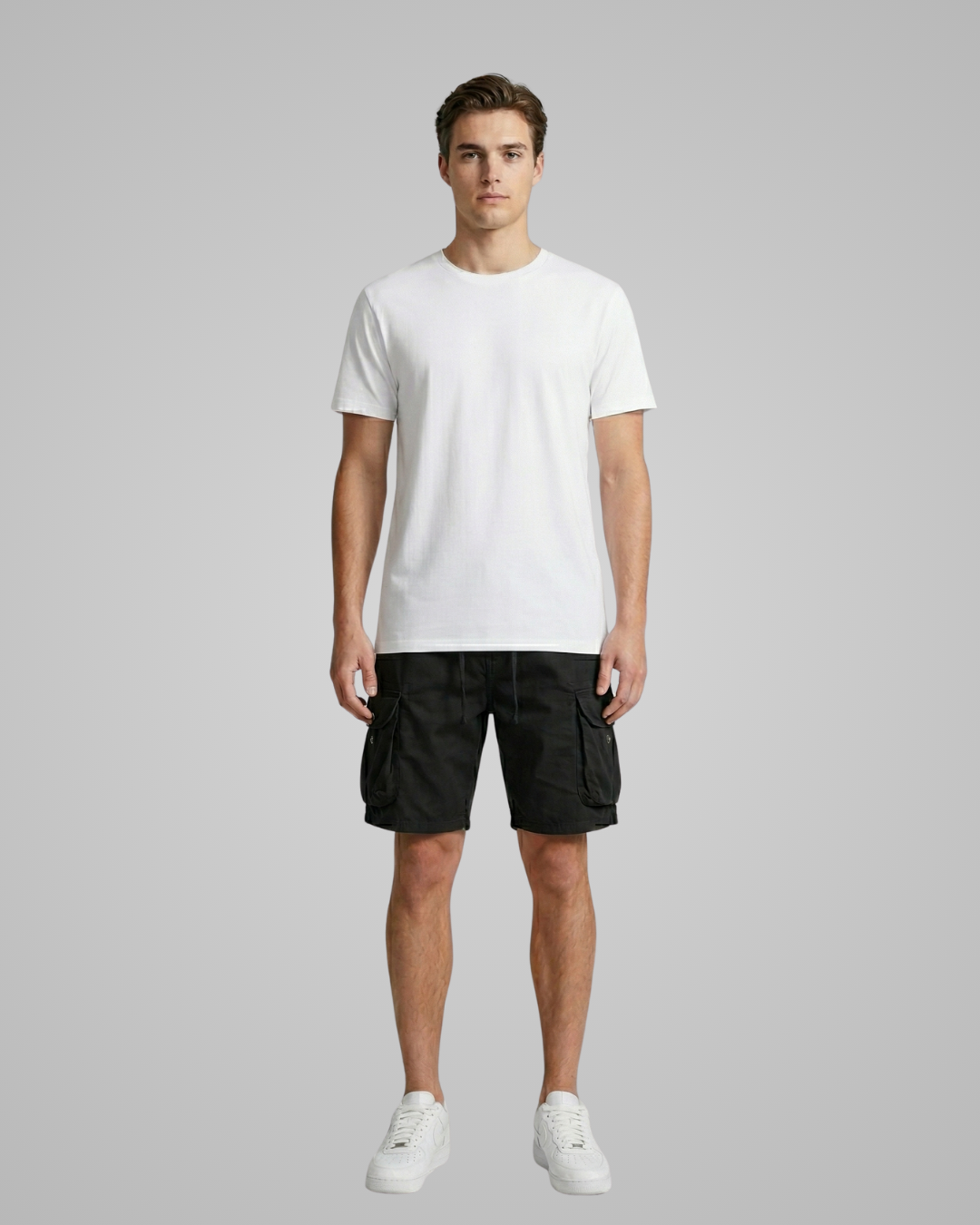 Man wearing a white t-shirt and black cargo shorts on a gray background