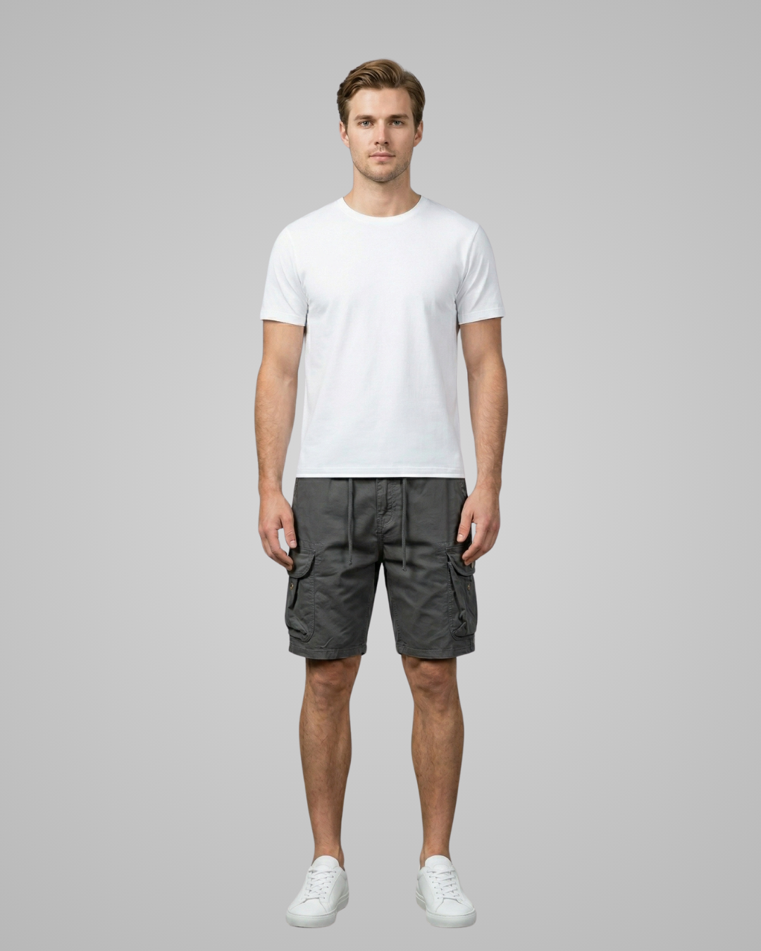 Man wearing a white t-shirt and gray cargo shorts on a gray background