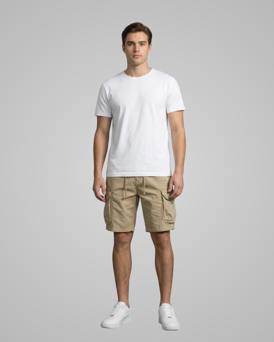 Man wearing a white t-shirt and beige cargo shorts on a gray background
