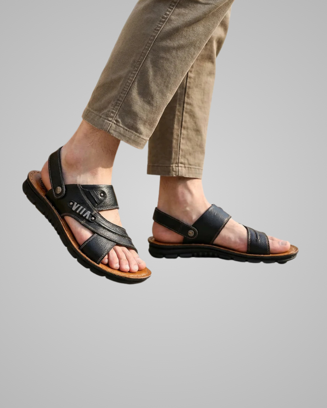 Black sandals worn with beige pants on a gray background