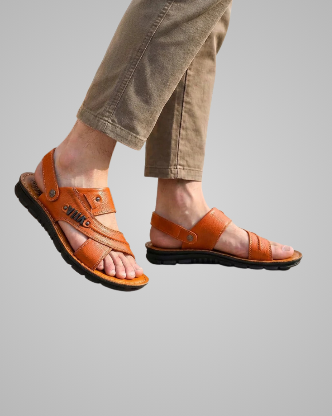 Brown sandals worn with beige pants on a gray background
