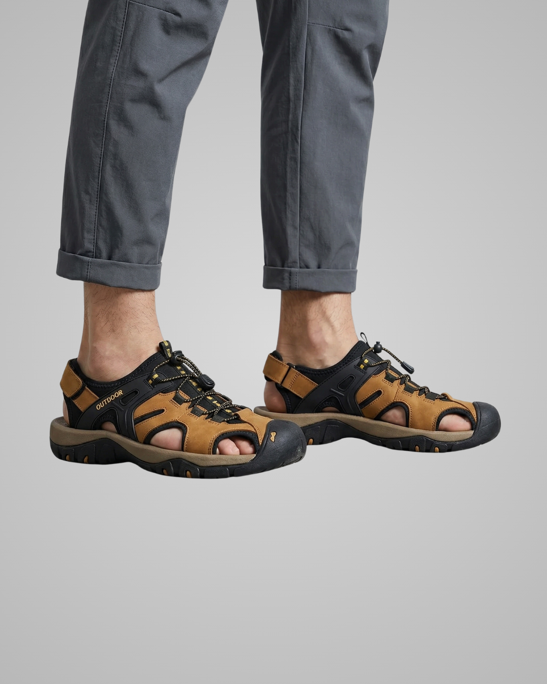 Brown and black sandals worn with gray pants on a light gray background