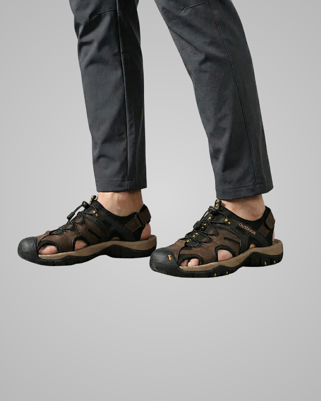Brown sandals worn with dark pants on a light gray background