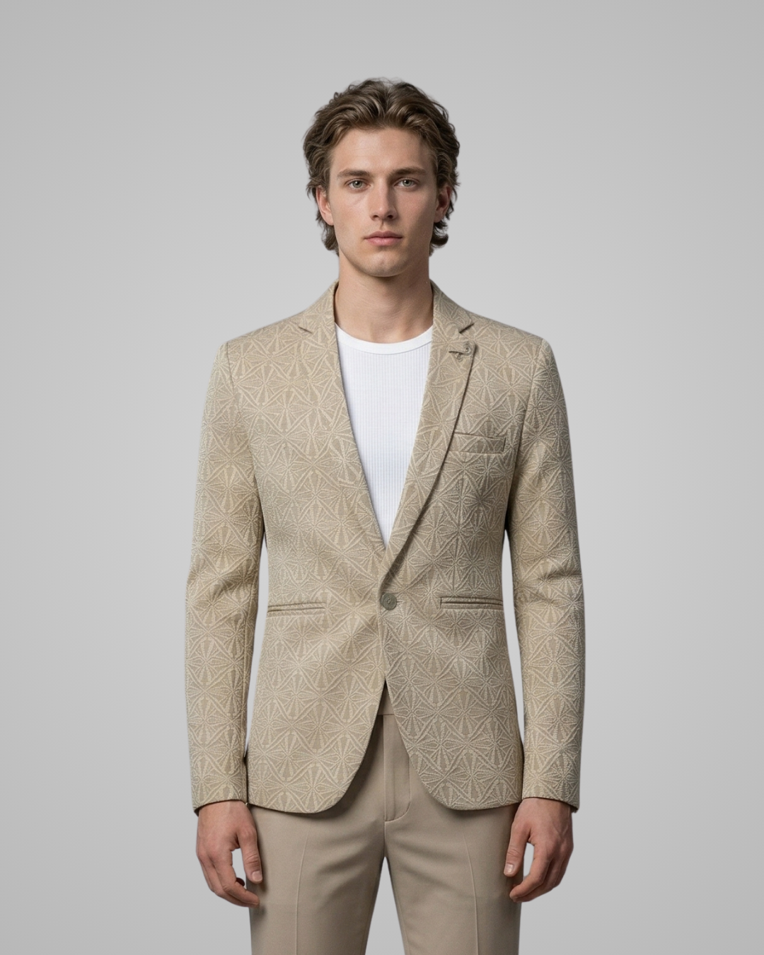 Man wearing a beige patterned blazer over a white shirt on a gray background