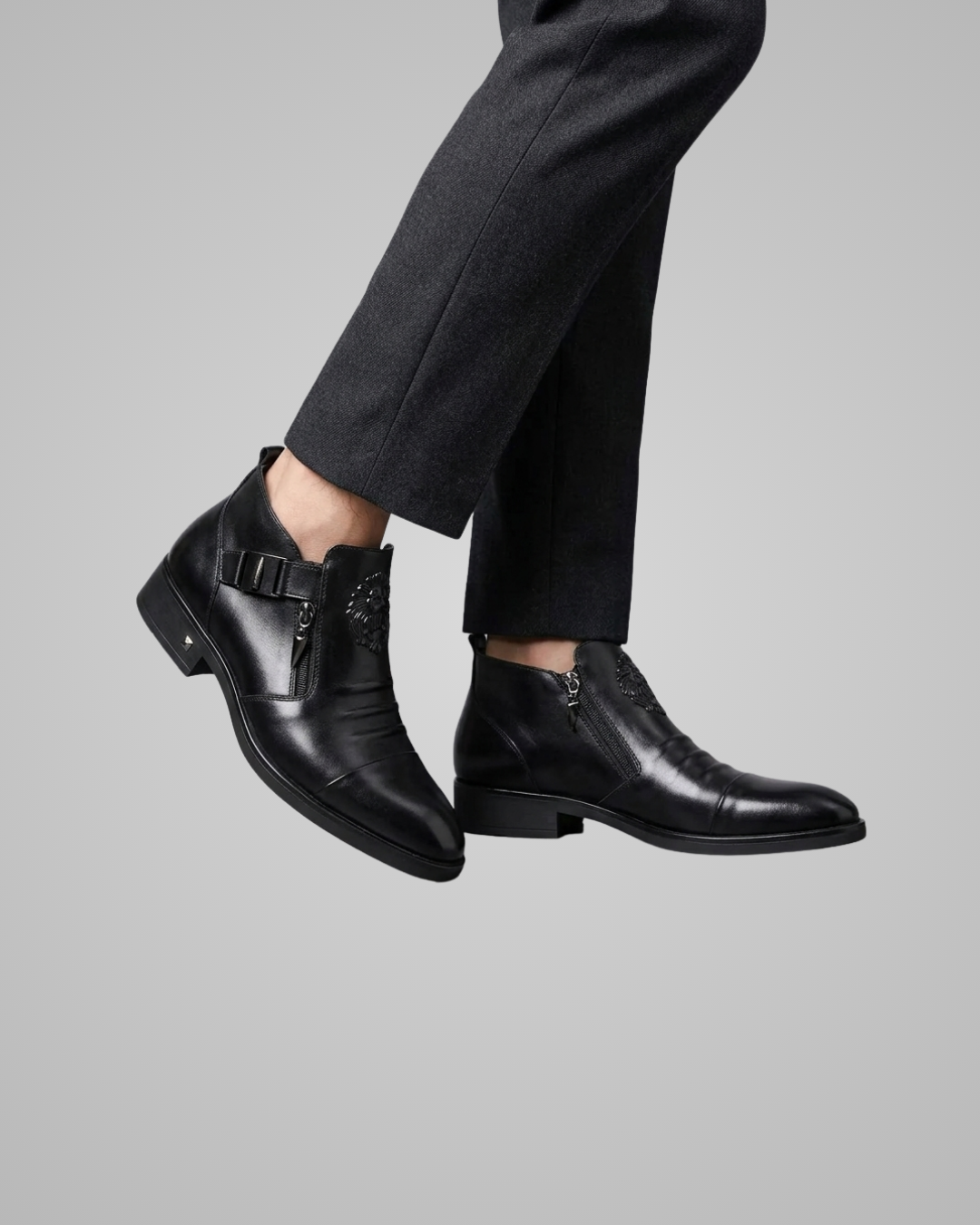 Black leather boots worn with black pants on a gray background