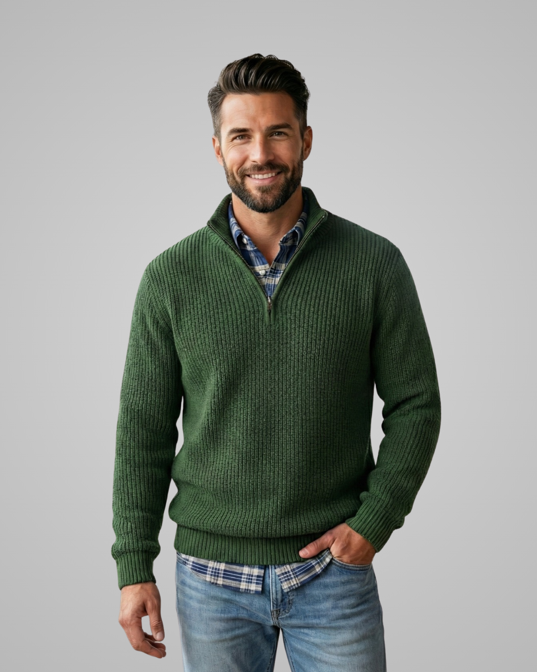 Man wearing a green sweater over a plaid shirt with a gray background