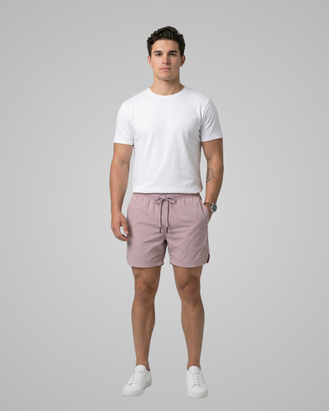 Man wearing a white t-shirt and pink shorts on a gray background