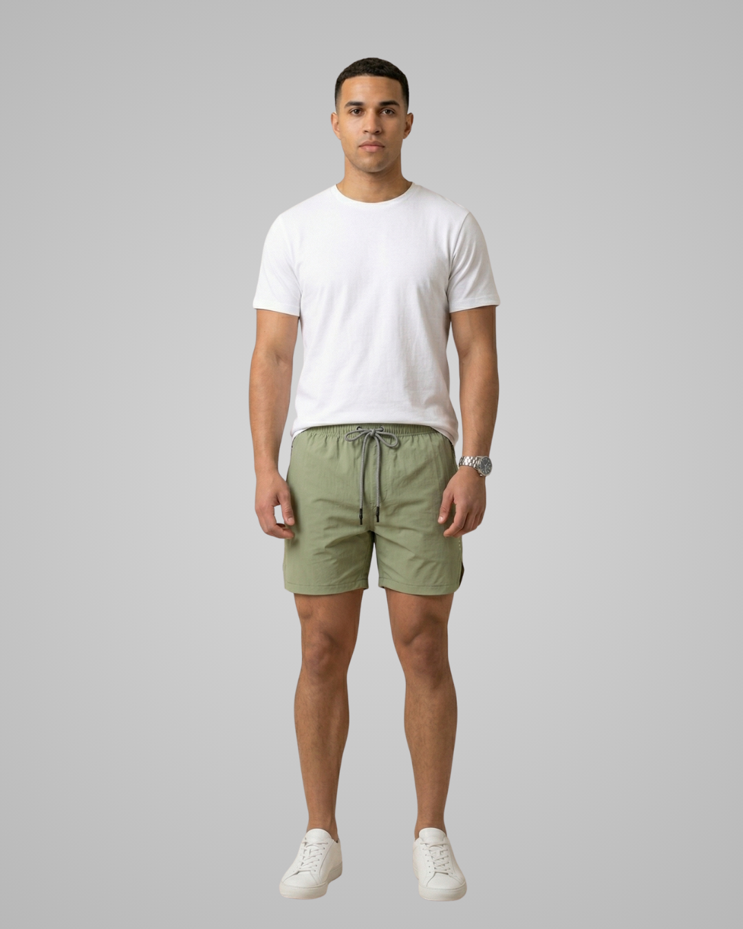 Man wearing a white t-shirt and green shorts on a gray background