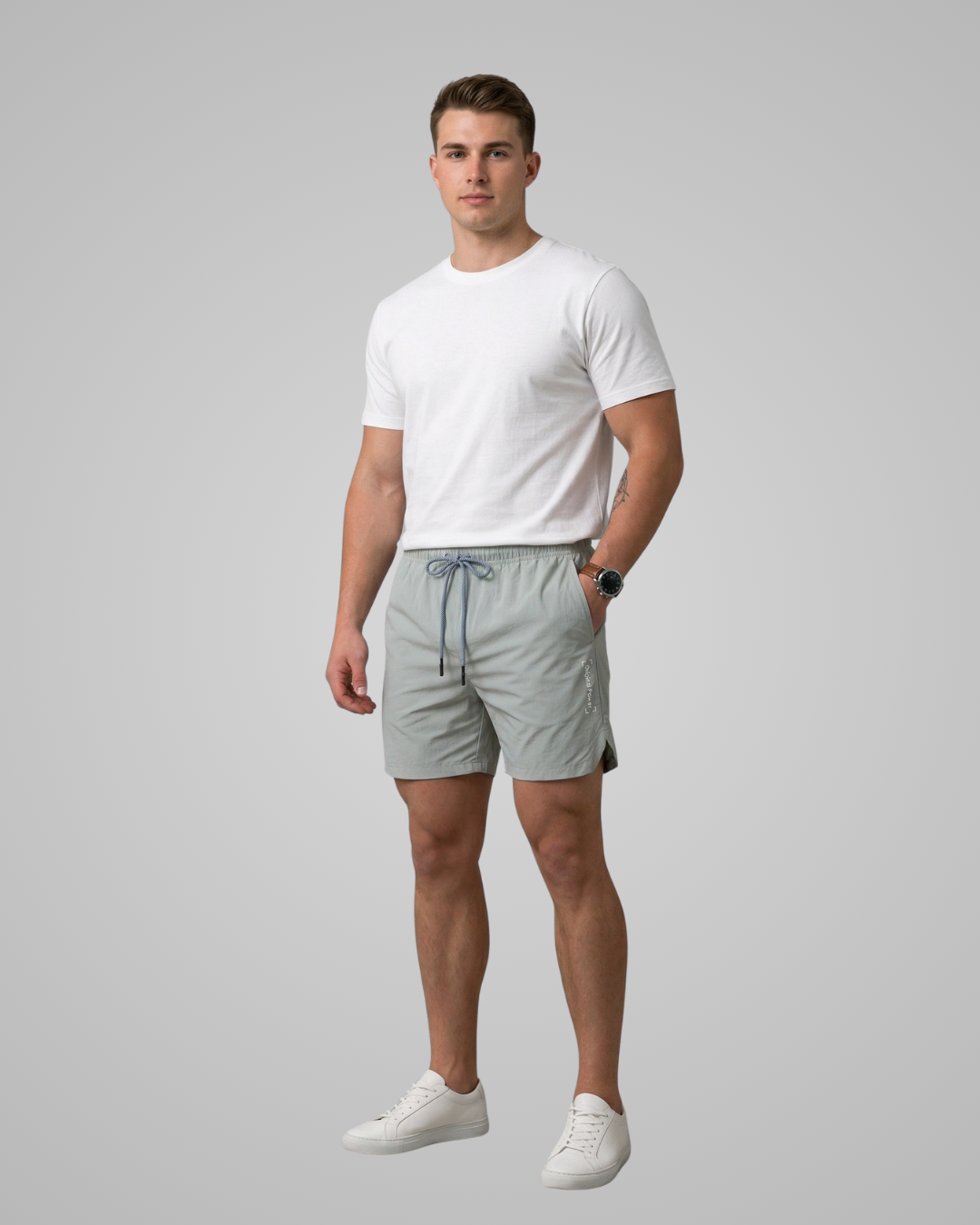 Man wearing a white t-shirt and light gray shorts on a gray background