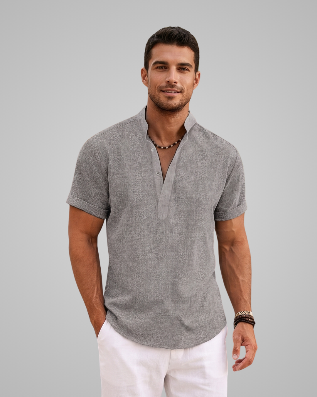 Man wearing a gray short-sleeve shirt and white pants against a gray background