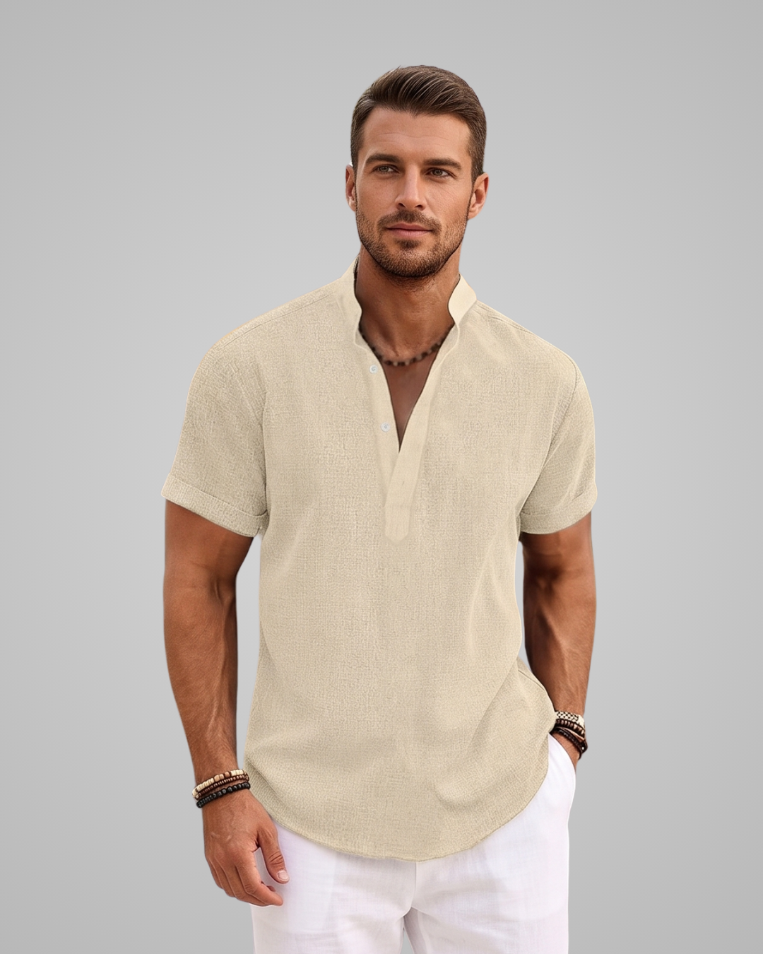 Man wearing a beige short-sleeve shirt and white pants against a gray background