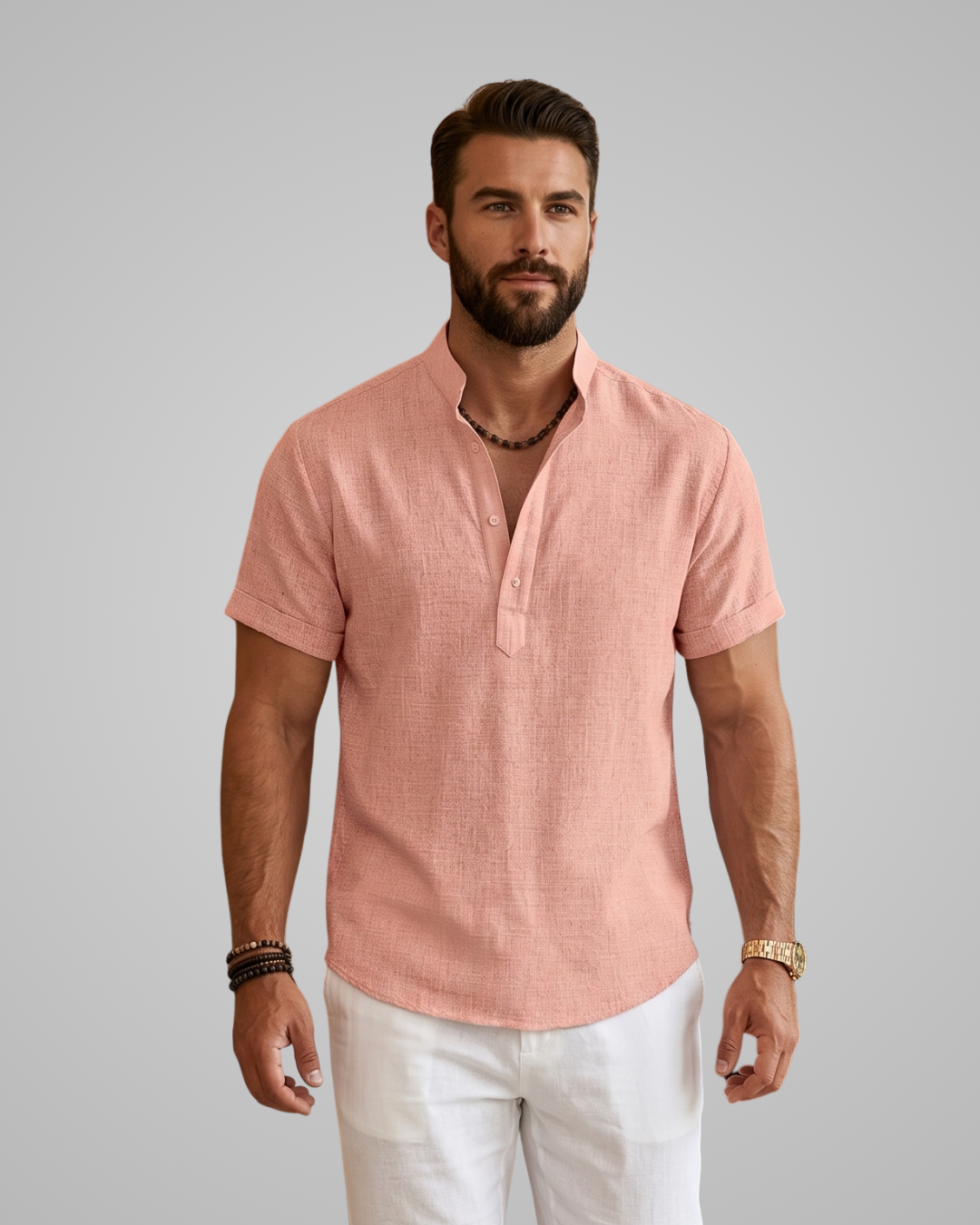 Man wearing a pink short-sleeve shirt and white pants against a gray background