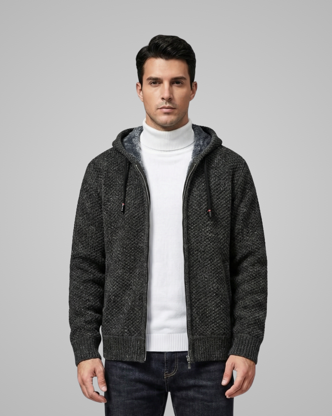 Man wearing a gray hooded jacket over a white turtleneck on a gray background