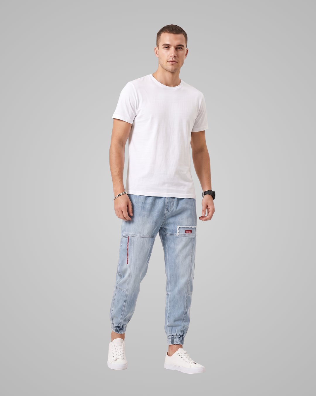 Man wearing a white t-shirt and light blue jeans on a gray background