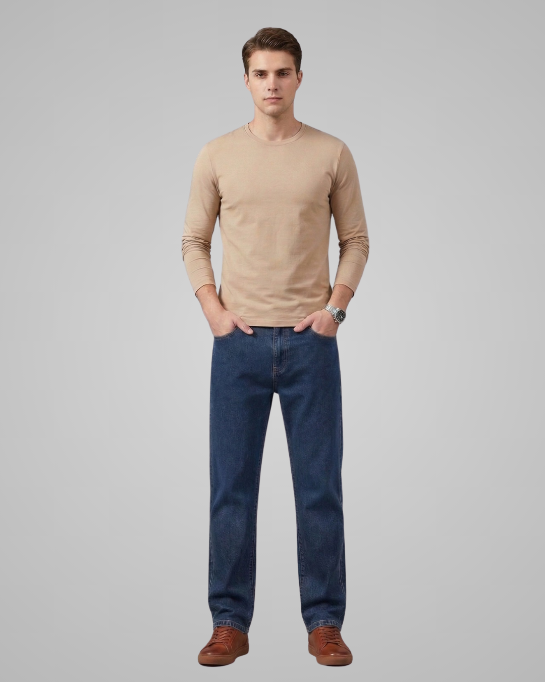 Man wearing a beige long-sleeve shirt and blue jeans on a gray background